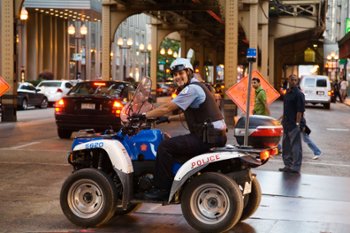 Police officer on an ATV in an urban setting, equipped with communication systems and safety gear, highlighting the adaptability of ATVs for city patrols