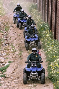 Law enforcement officers patrolling rugged terrain on ATVs, equipped with helmets for safety, showcasing the use of off-road units in challenging environments.